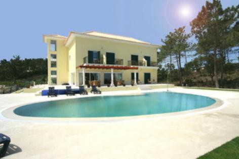 a large swimming pool in front of a house at Hotel Soltroia - Foz Do Sado in Troia