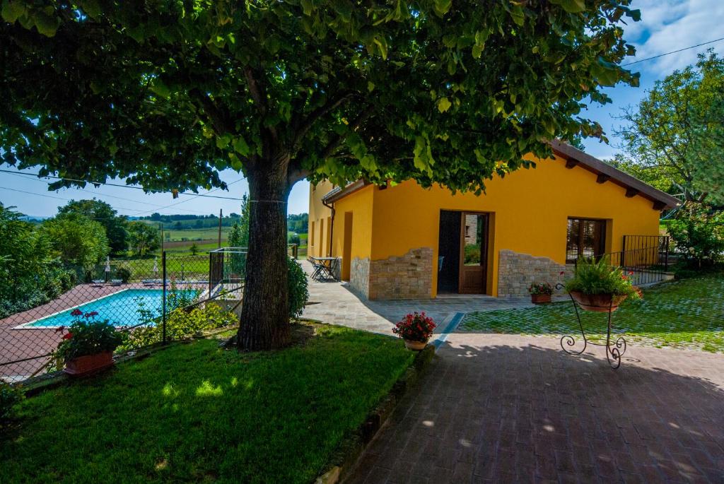 uma casa amarela com uma árvore e uma piscina em Country House Il Tiglio em Mergo