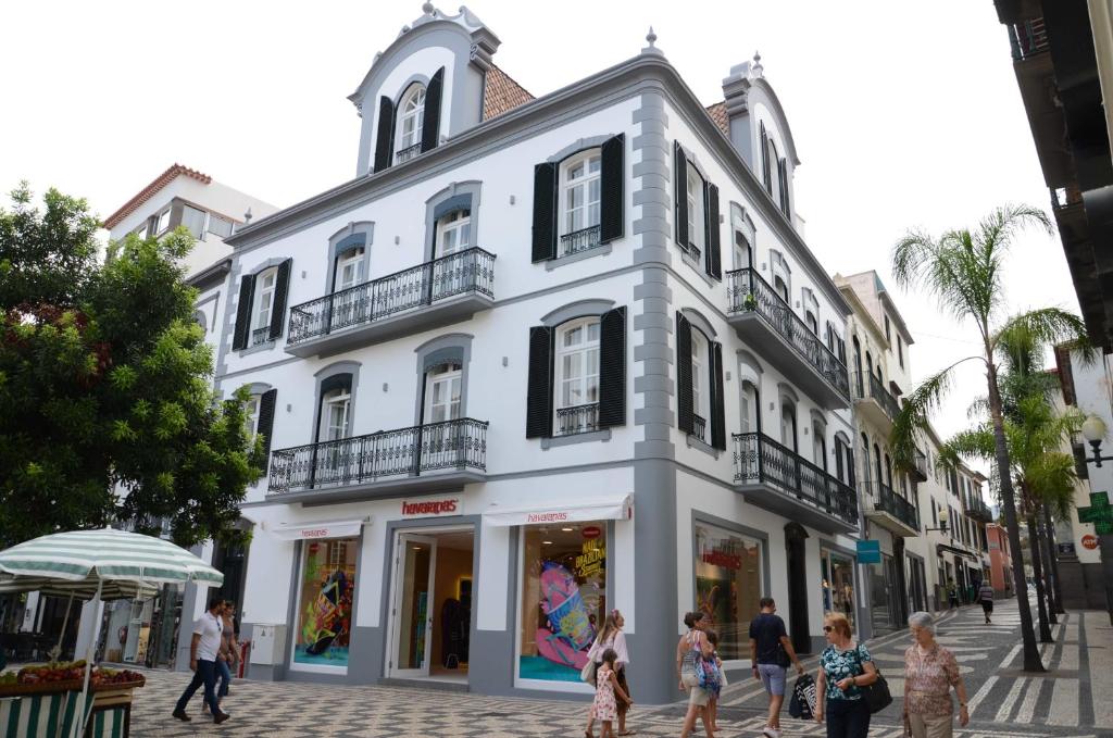 Un bâtiment blanc avec des gens qui marchent devant lui dans l'établissement Edifício Charles 203, à Funchal