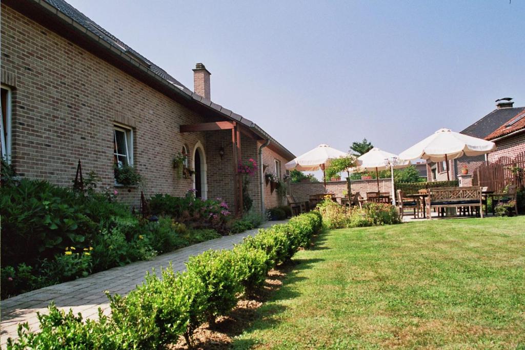 einen Garten mit Sonnenschirmen neben einem Gebäude in der Unterkunft Hotel In Den Hoek in Tielt