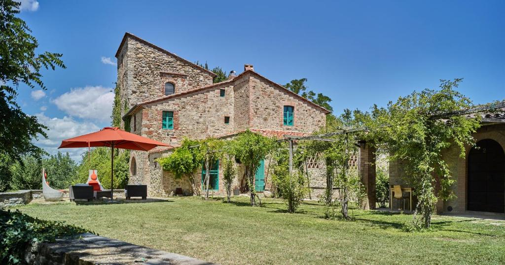 - un grand bâtiment en pierre avec un parasol dans la cour dans l'établissement Torre di Pornello, à Pornello