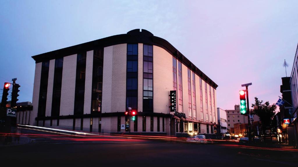 ein großes Gebäude an einer Stadtstraße mit Ampeln in der Unterkunft Hotel Chicoutimi in Saguenay