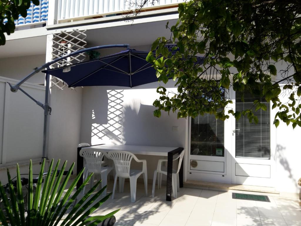 une terrasse avec une table, des chaises et un parasol dans l'établissement Villa Flora, à Grado