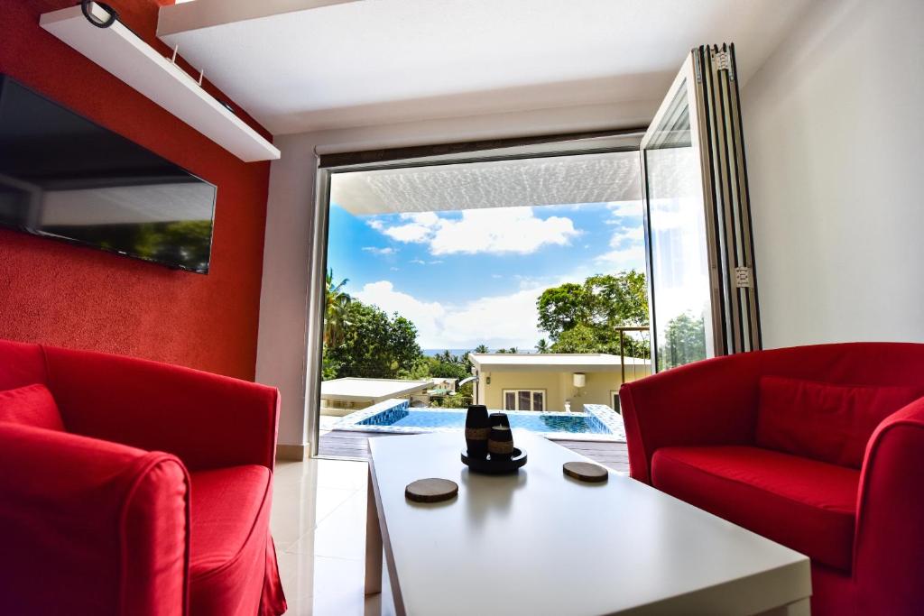 a living room with red chairs and a white table at Moulin Kann Villas in Mahe