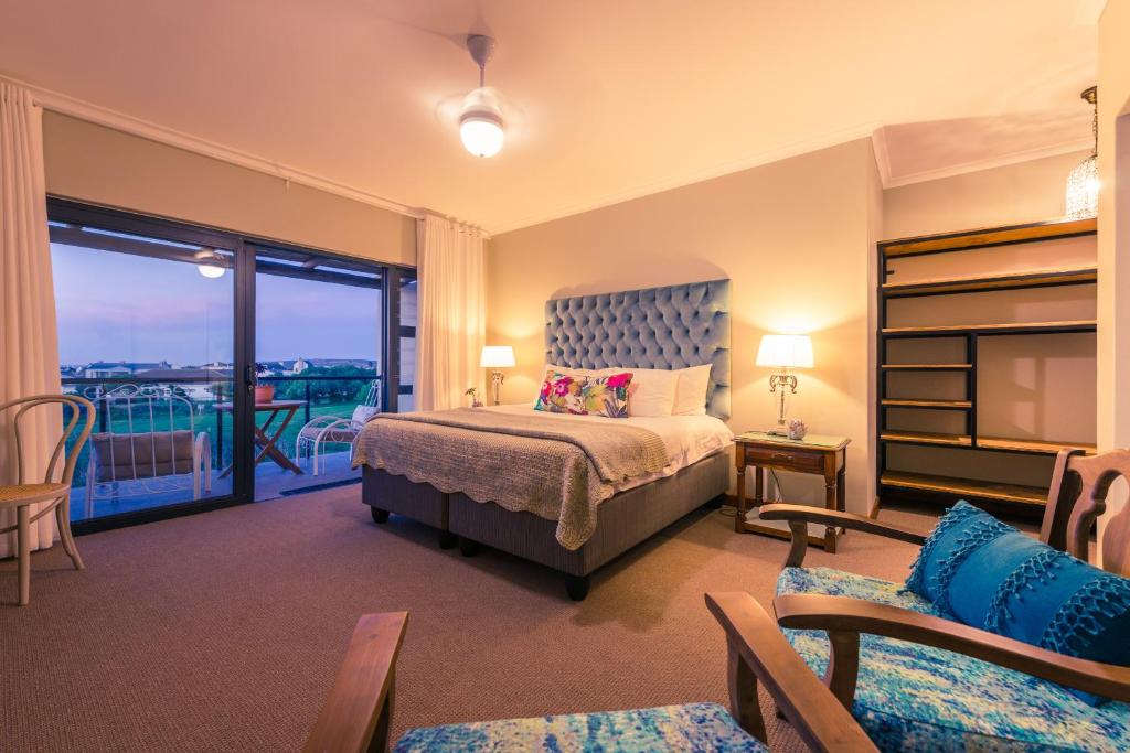 a bedroom with a bed and a balcony at Le Mahi Guest House in Langebaan