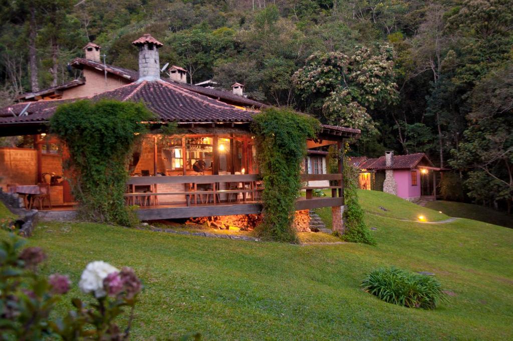 ein Haus auf einem grasbewachsenen Hügel mit einem Gebäude in der Unterkunft Pousada Tijupá in Visconde De Maua