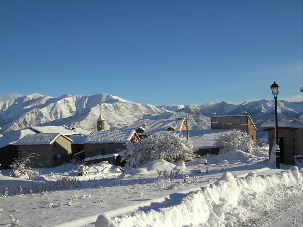 una ciudad cubierta de nieve con montañas en el fondo en La Voz del Silencio en Neril