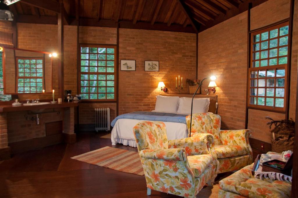 a bedroom with a bed and a couch and a chair at Pousada Tijupá in Visconde De Maua