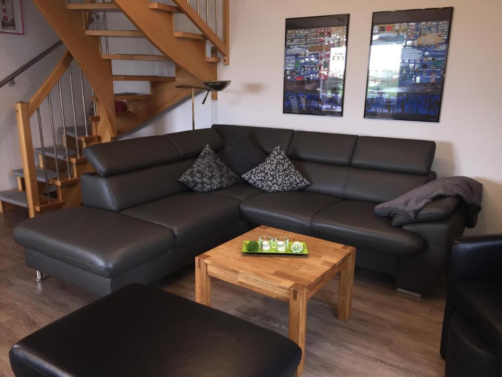 ein Wohnzimmer mit einem schwarzen Sofa und einem Tisch in der Unterkunft Skippersin4 in Greetsiel