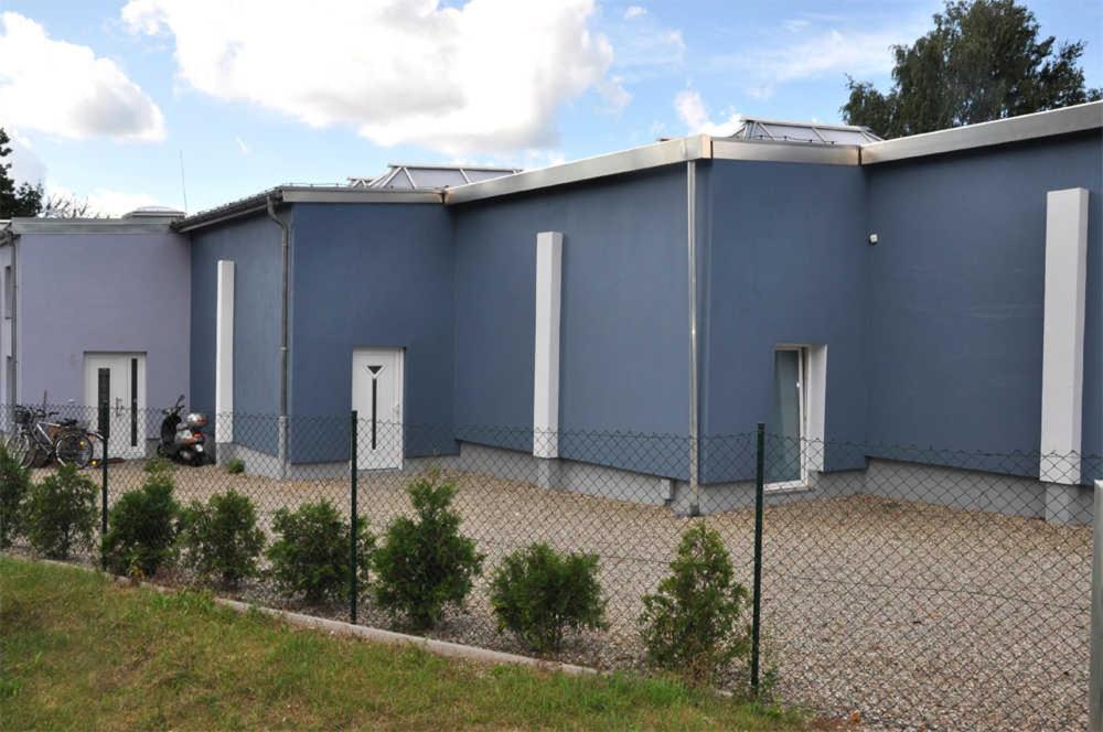 a blue building with white doors and a fence at Ferienhaus Neubrandenburg SEE 8711 in Neubrandenburg