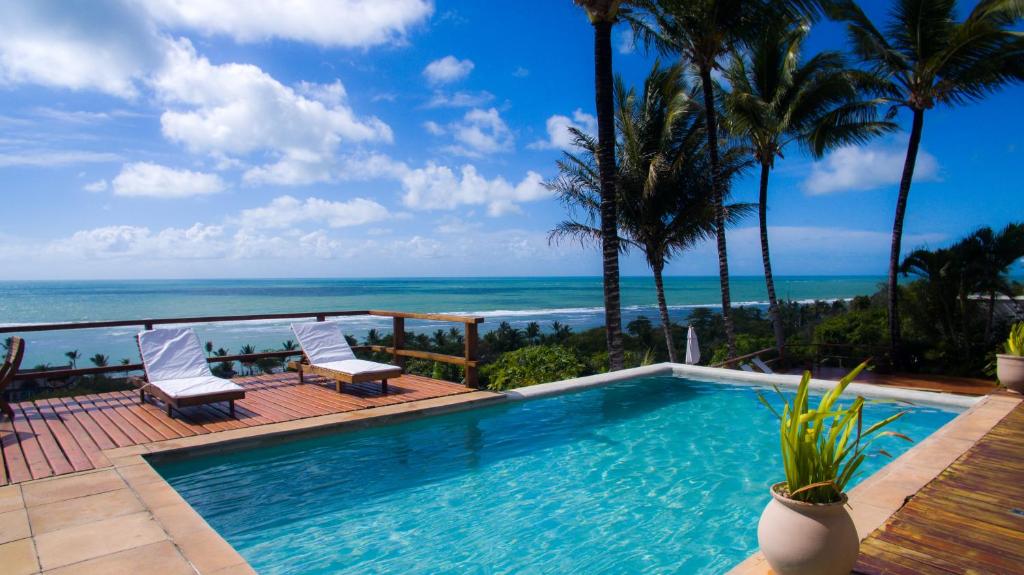 a swimming pool with a view of the ocean at Baixu Village in Arraial d'Ajuda