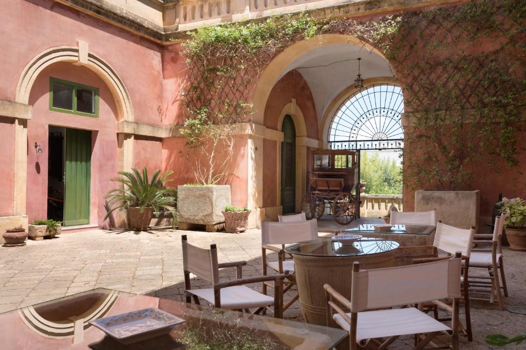 un patio con tavoli e sedie in un edificio di Palazzo Laura a Morciano di Leuca