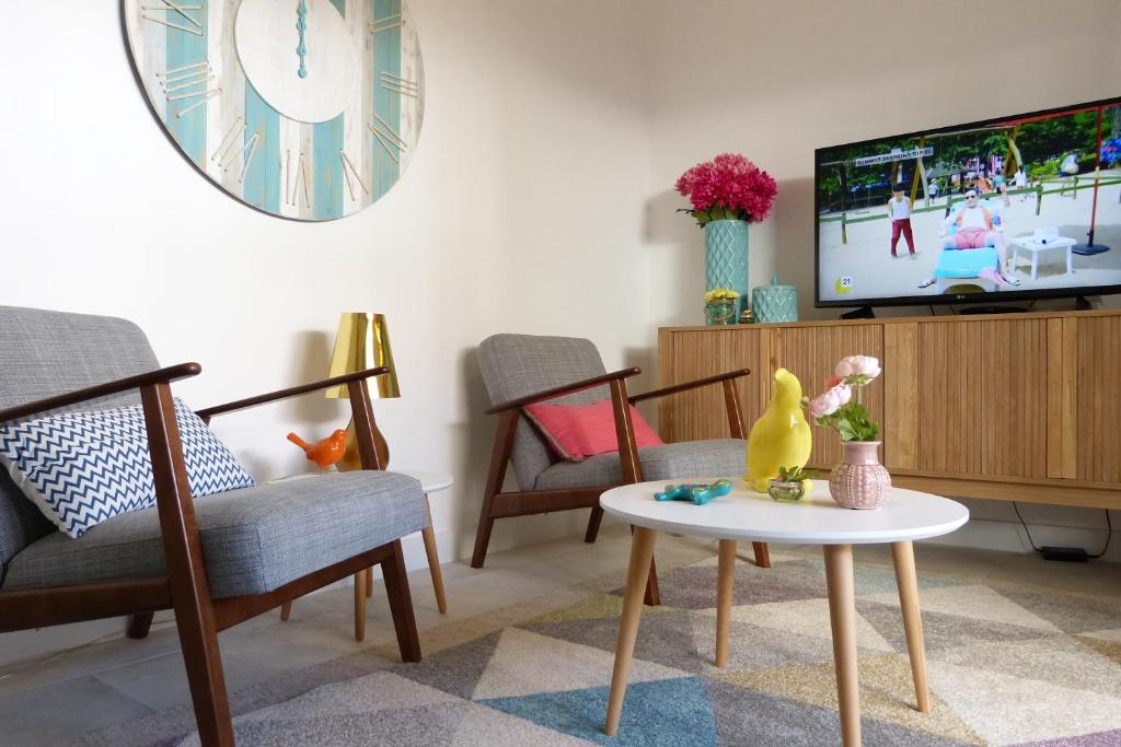 a living room with chairs and a table and a tv at Palhas apartment in Ericeira