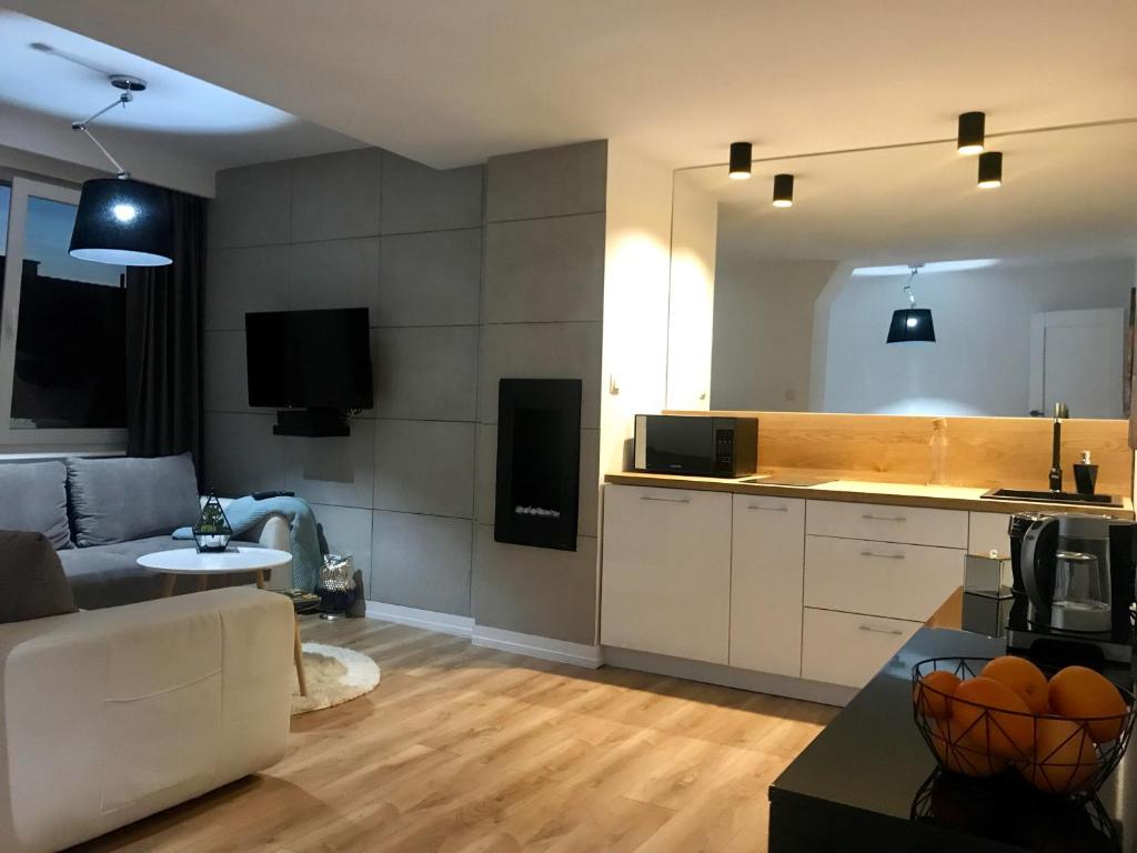 a living room with a white couch and a kitchen at Apartament Mozart in Gdańsk