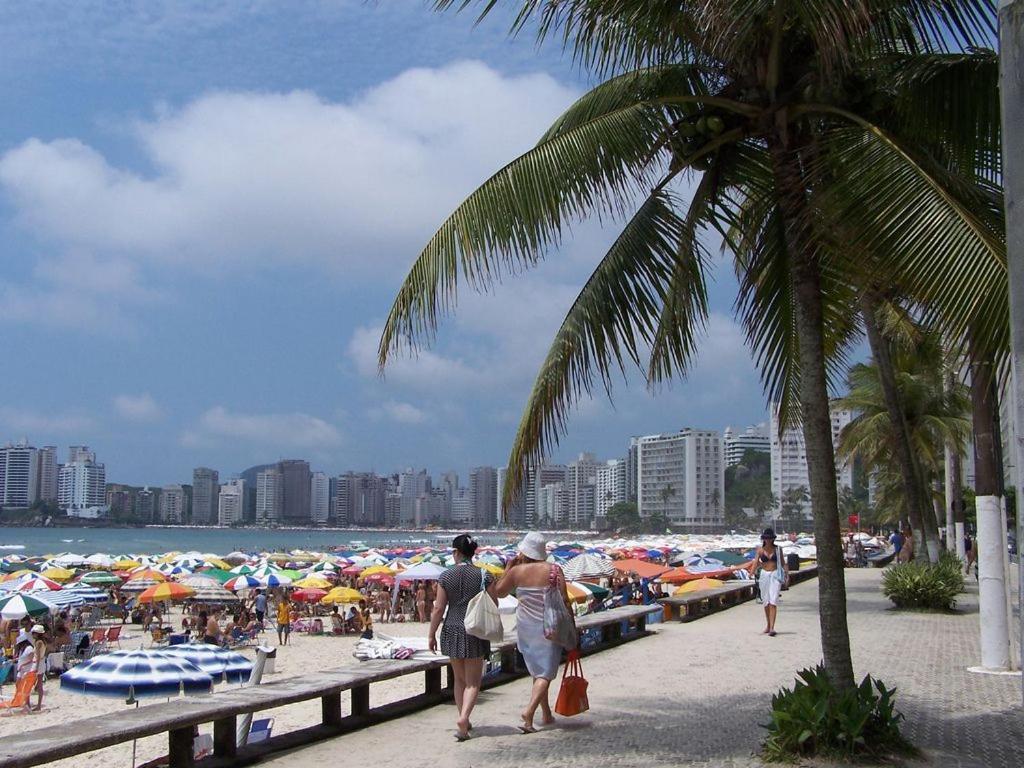 un grupo de personas caminando por una playa con sombrillas en Apartamento Estúdio na Pitangueiras en Guarujá