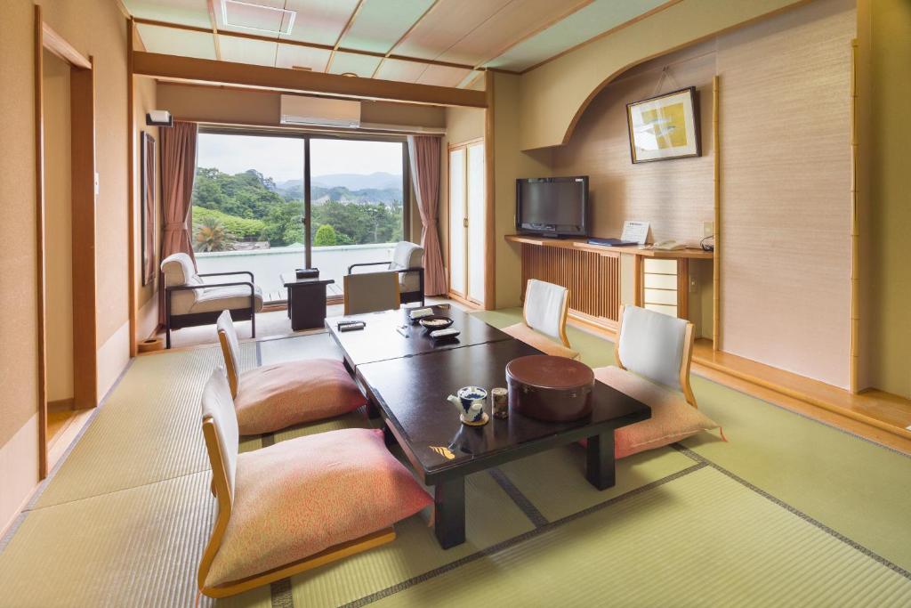 a room with a table and chairs and a television at Dogashima Onsen Hotel in Nishiizu