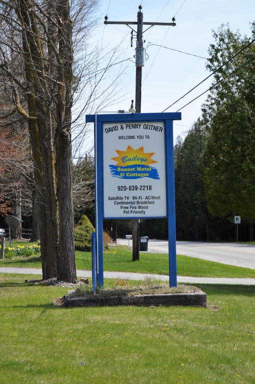 a sign in the grass next to a street at Baileys Sunset Cottages in Baileys Harbor