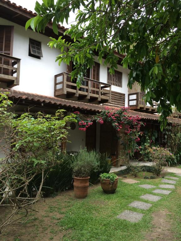 a house with two balconies and plants in the yard at Conforto e Charme em Ilhabela in Ilhabela