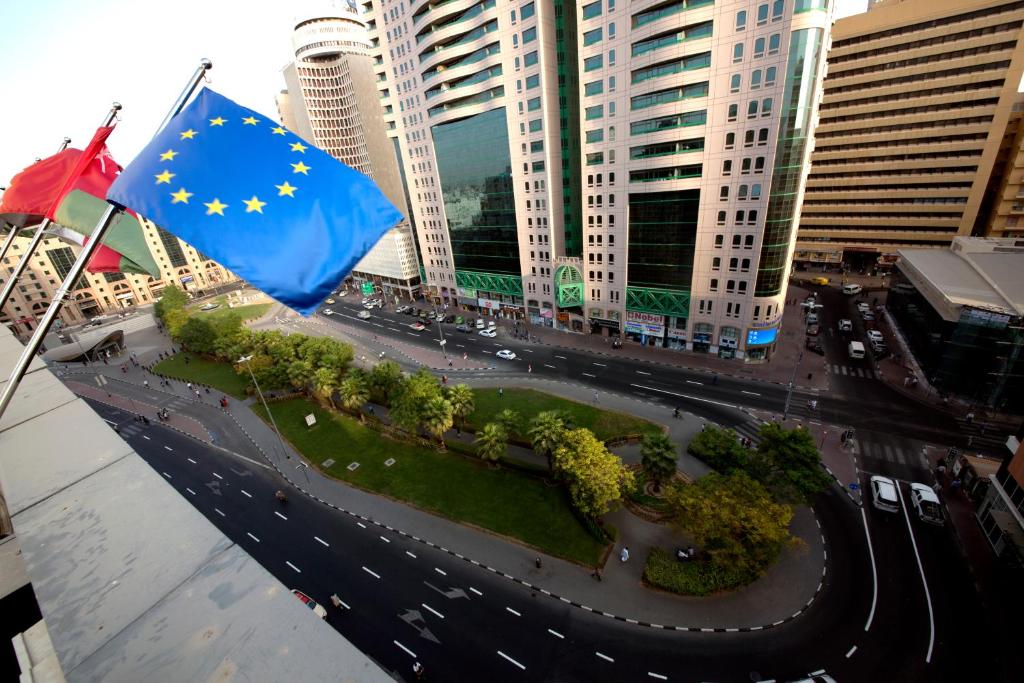 a european flag flying over a street with buildings at White Fort Hotel in Dubai