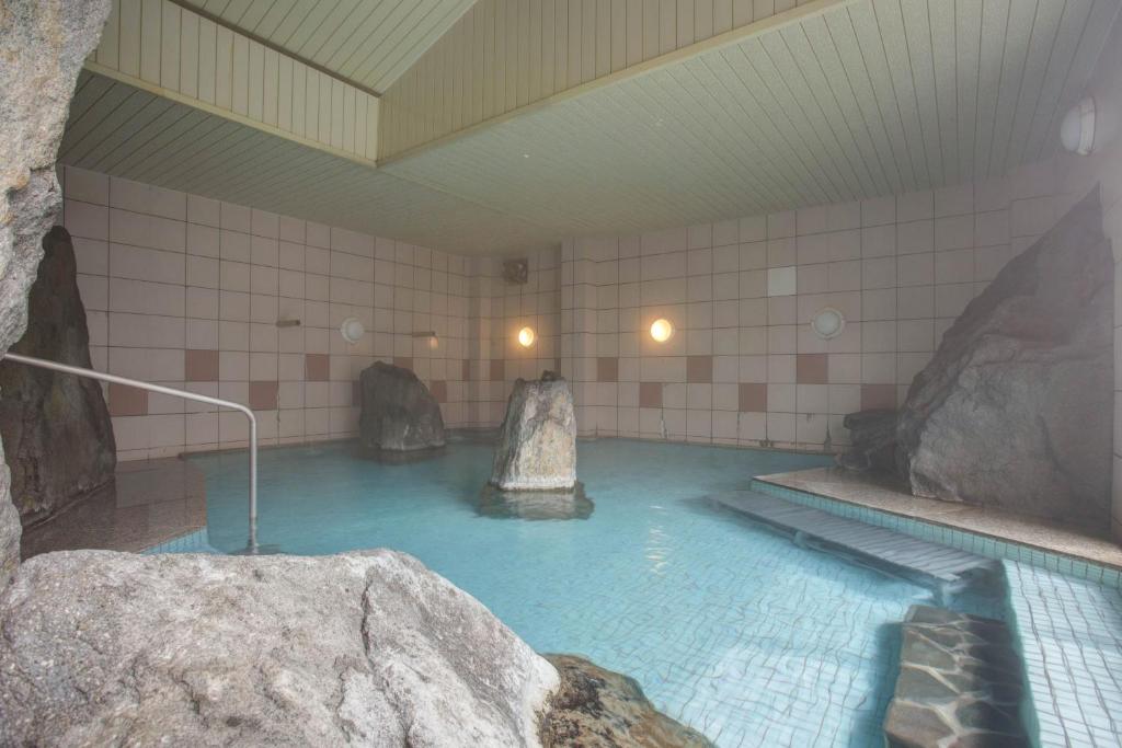 a pool of water in a room with rocks at Hotel Heian in Fuefuki