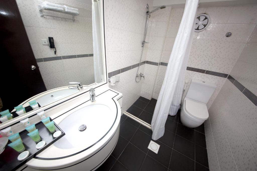 a bathroom with a toilet and a sink and a mirror at White Fort Hotel in Dubai