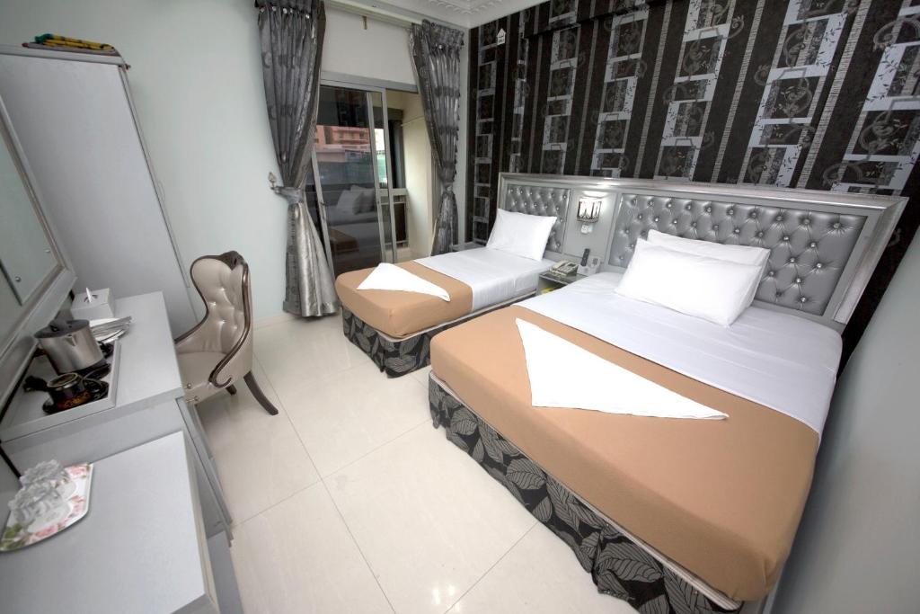 a small bedroom with two beds and a mirror at White Fort Hotel in Dubai