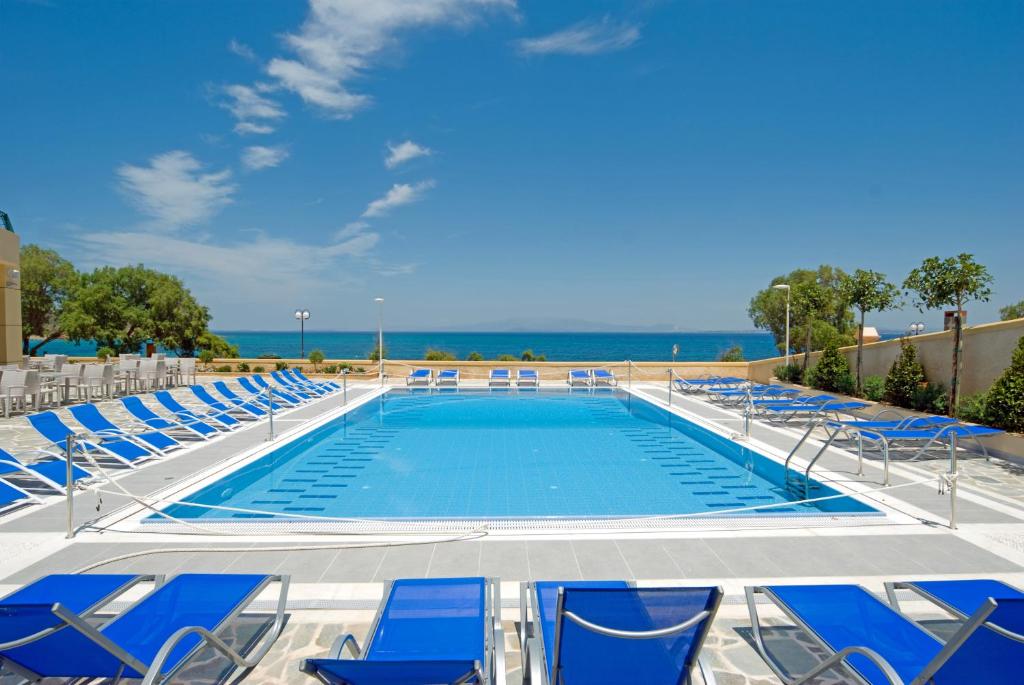 a swimming pool with chairs and the ocean in the background at Aegean Dream Hotel in Karfas