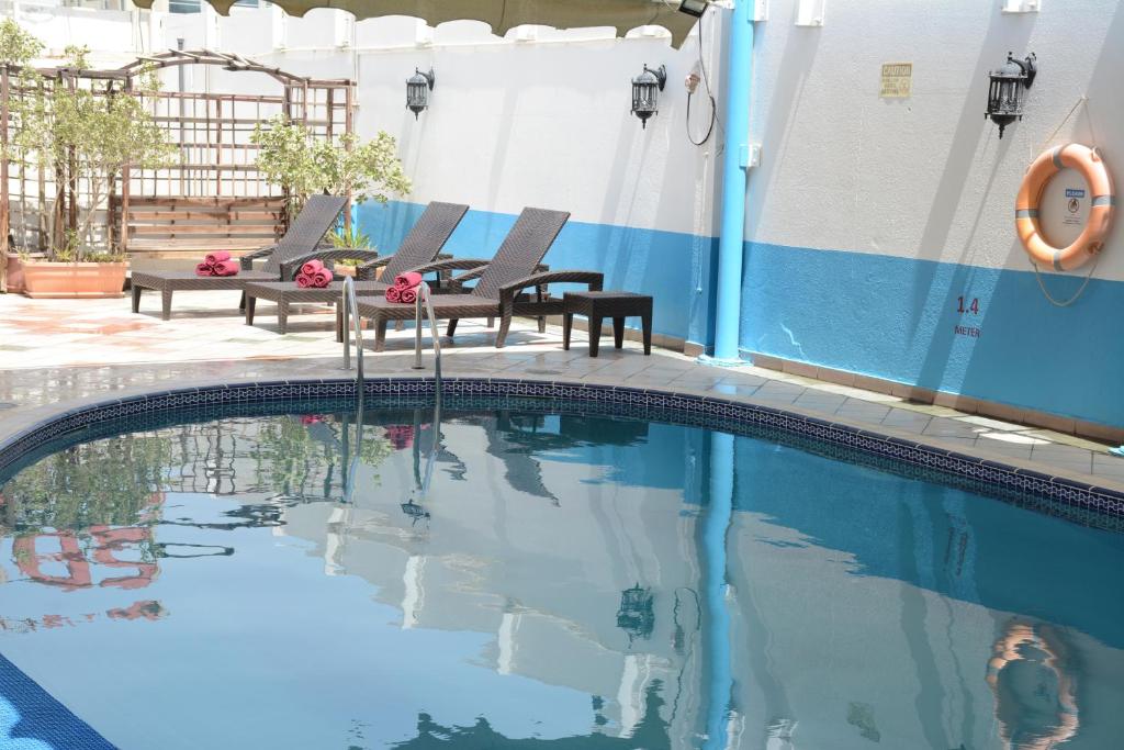 a swimming pool with two chairs and a table at Spark Residence Hotel in Sharjah
