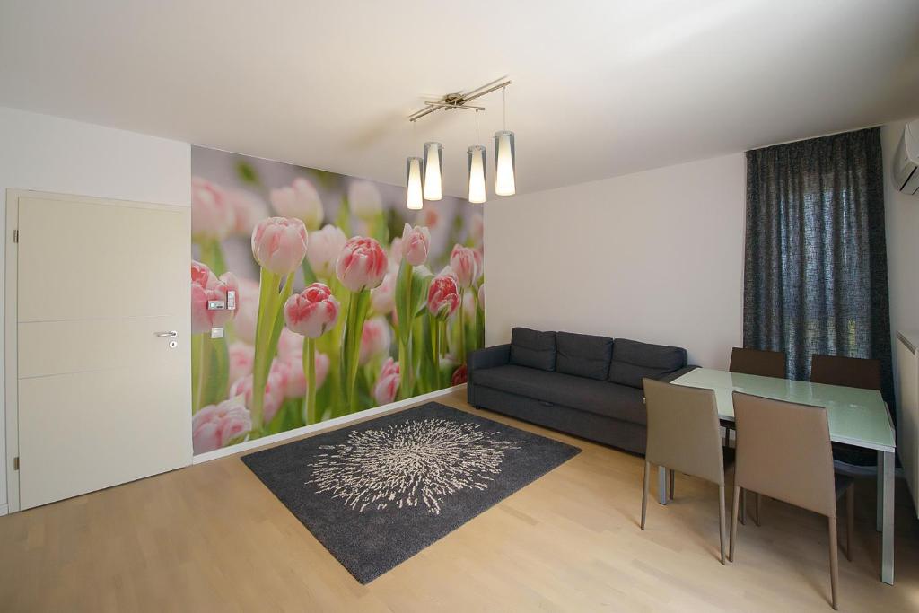 ein Wohnzimmer mit einem Sofa und einem Tisch mit rosa Blumen in der Unterkunft Apartamente Olivero in Braşov
