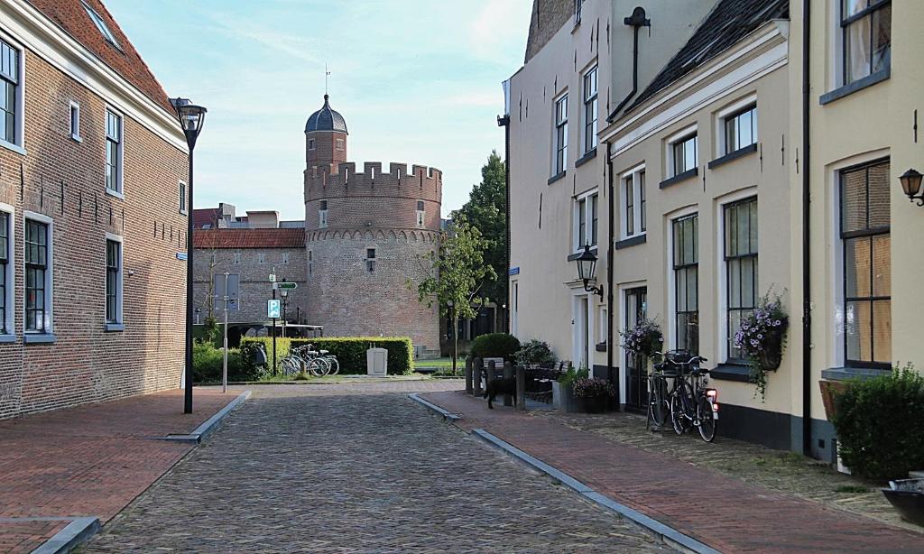 uma rua de calçada em frente a um castelo em De Pelsertoren em Zwolle