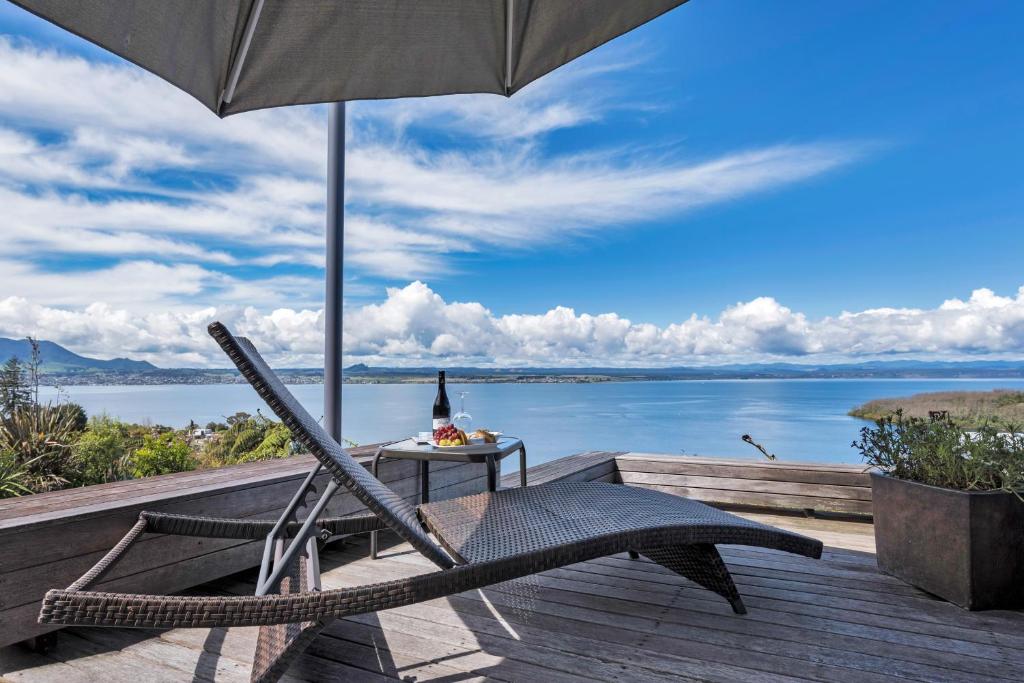 a chair sitting on a deck with an umbrella at Serenity On Wakeman in Taupo