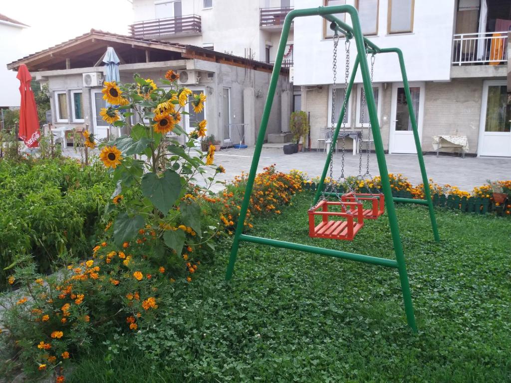 un columpio verde en un jardín con un ramo de girasoles en Apartments Nasteski, en Ohrid