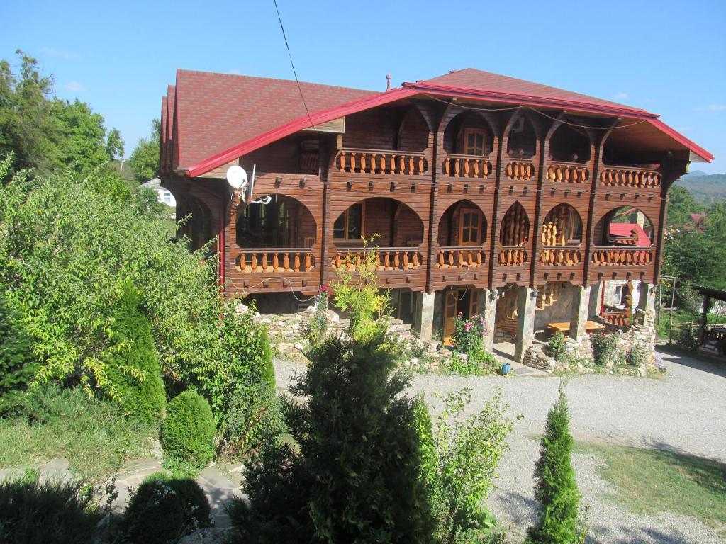 a large wooden house with a red roof at Guesthouse Lyubava in Kamennomostskiy