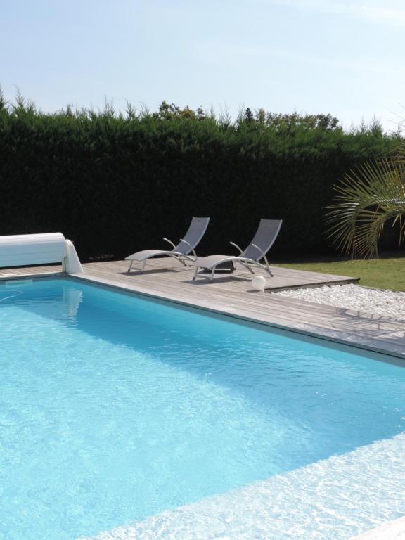 una piscina con 2 tumbonas junto a ella en Maison d'Amis, en Salles