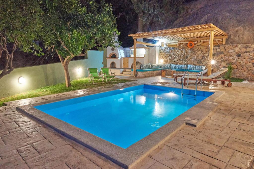 a swimming pool in a backyard at night at Pura Vida in Rodakino