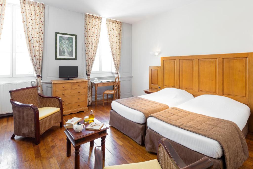 サラン・レ・バンにあるAppart Hotel Charles Sanderのベッド2台とデスクが備わるホテルルームです。