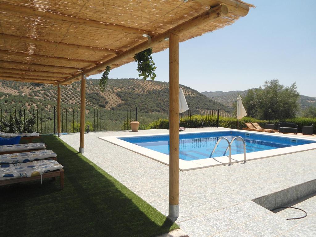 a swimming pool with a wooden pergola and a swimming poolvisor at B&B Lasnavillasmm in Montefrío