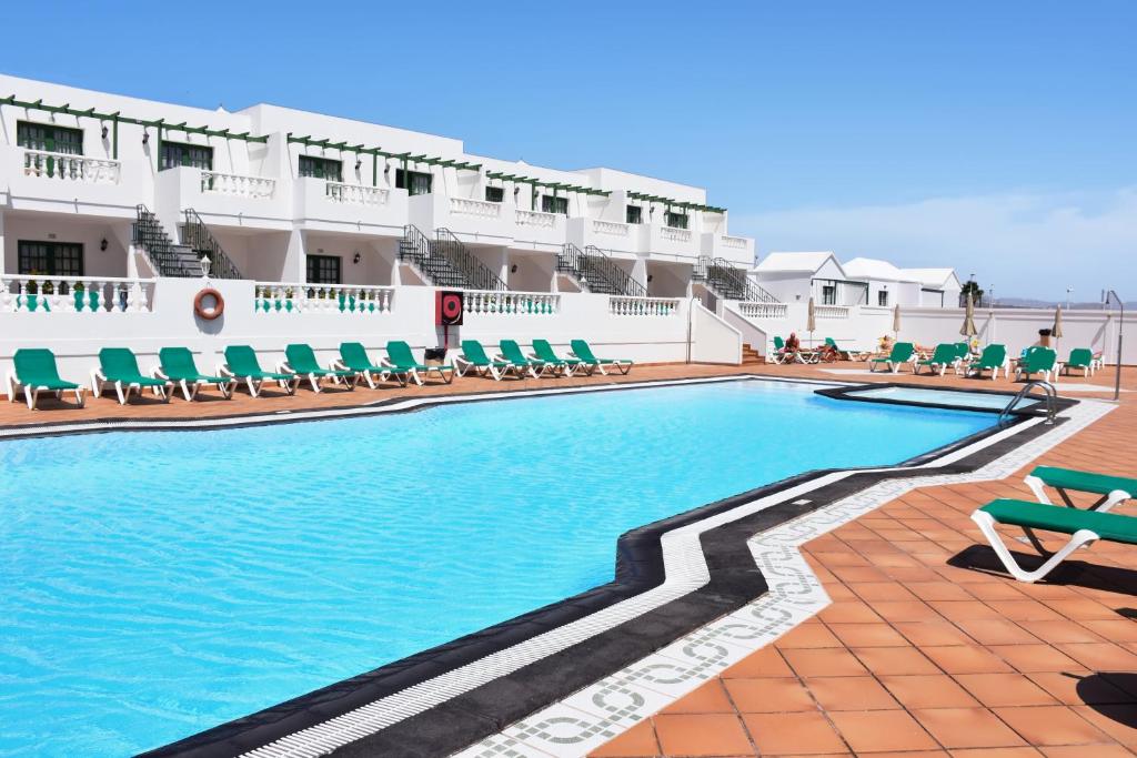 una piscina con sillas y un hotel en Apartamentos Tisalaya, en Puerto del Carmen