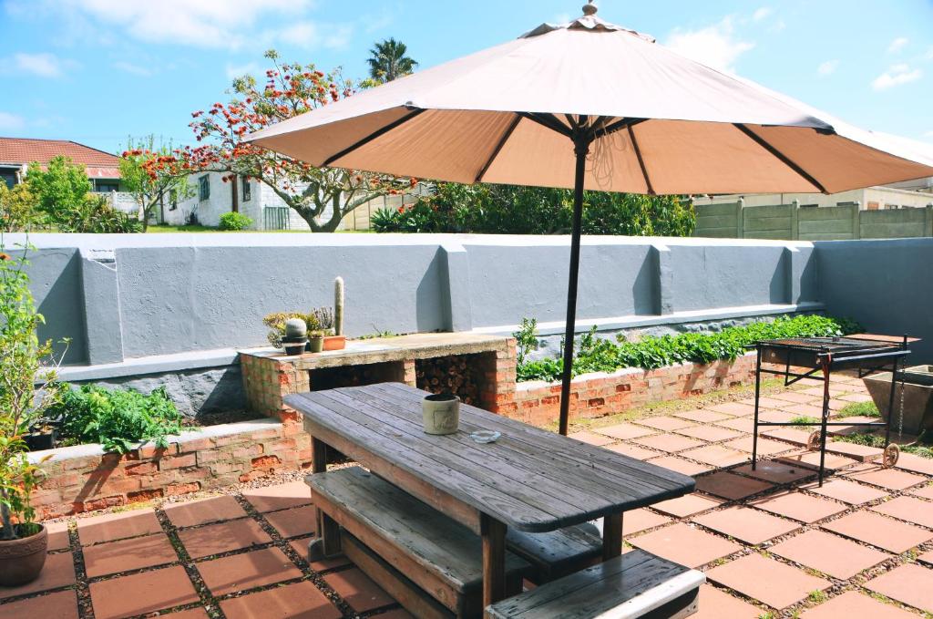 a picnic table with an umbrella on a patio at House Forget Me Not in Bredasdorp