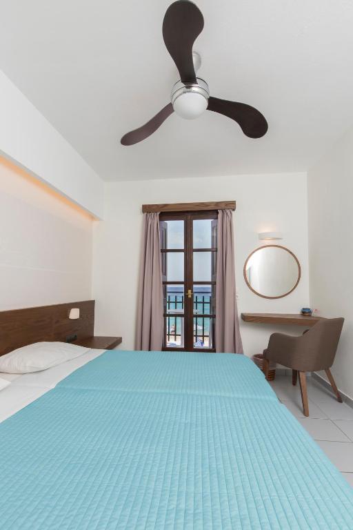 ein Schlafzimmer mit einem blauen Bett und einem Deckenventilator in der Unterkunft Long Beach Kokkari Samos in Kokkari