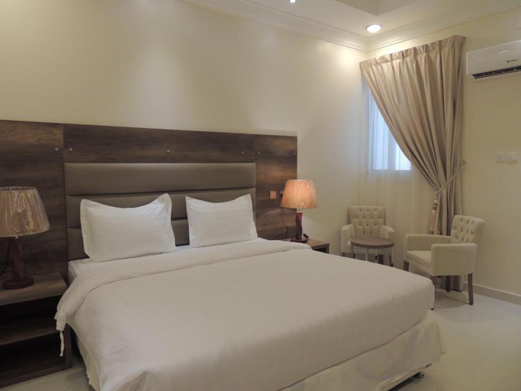 Un dormitorio con una gran cama blanca y una ventana en Golden Square, en Khamis Mushayt