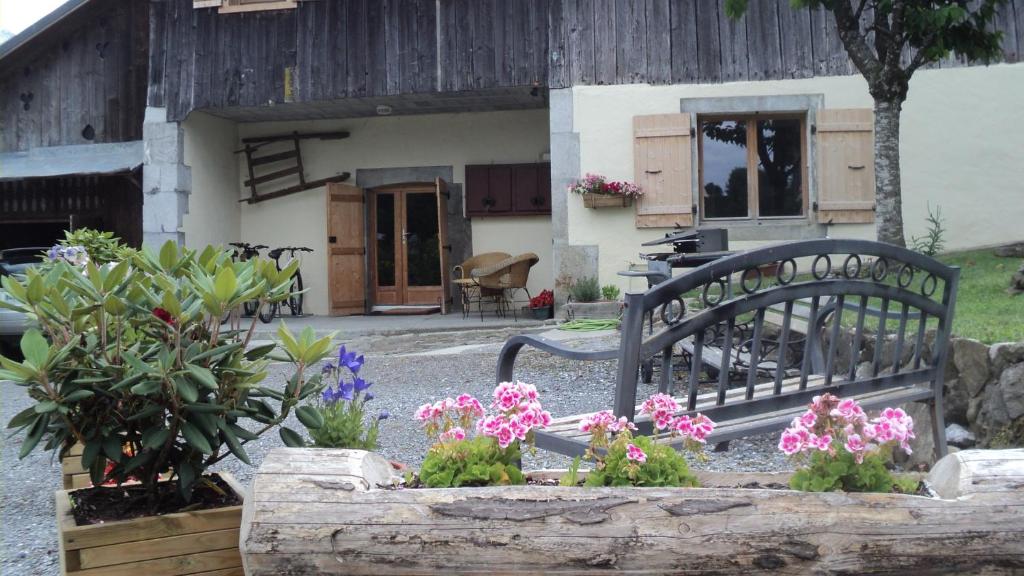 a bench in front of a house with flowers at Ferme Dowena in Morillon