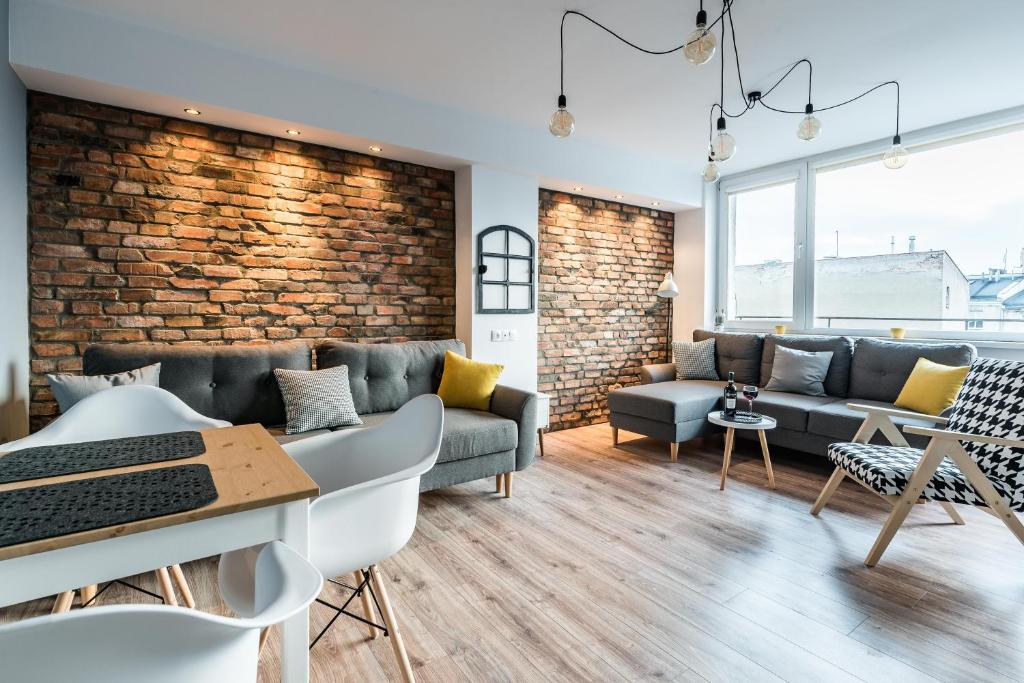 a living room with couches and a brick wall at Stylish Apartment Posnania City Center in Poznań