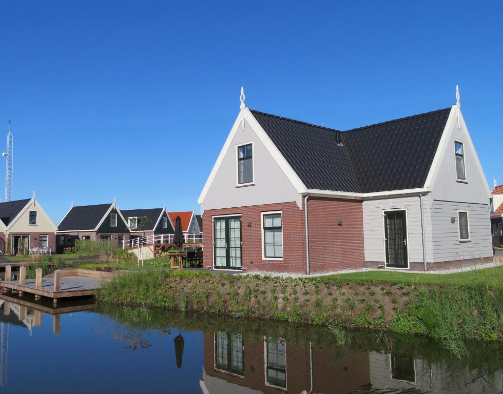 a house with a black roof next to a river at Luxurious Water Villa in Uitdam