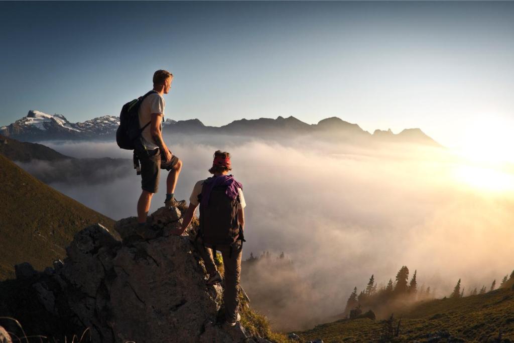 two people standing on top of a mountain overlooking a foggy valley at Hotel Engelberg "mein Trail Hotel" in Engelberg