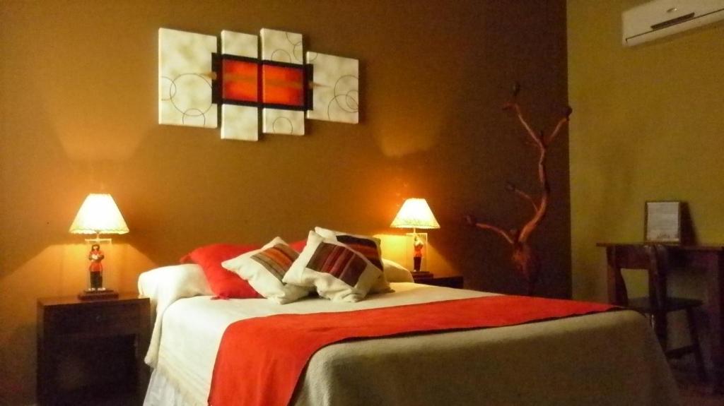 a bedroom with a bed with red and white pillows at Cerro de la Cruz in Cafayate