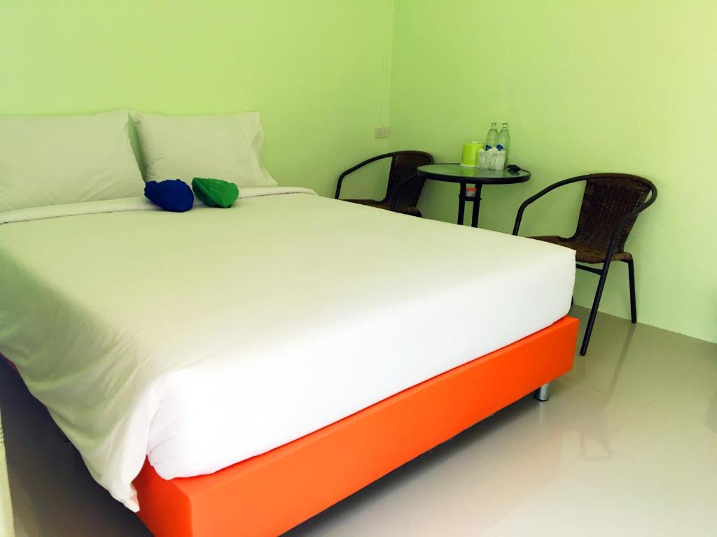 a bed in a room with two chairs and a table at Go Green Resort in Chumphon