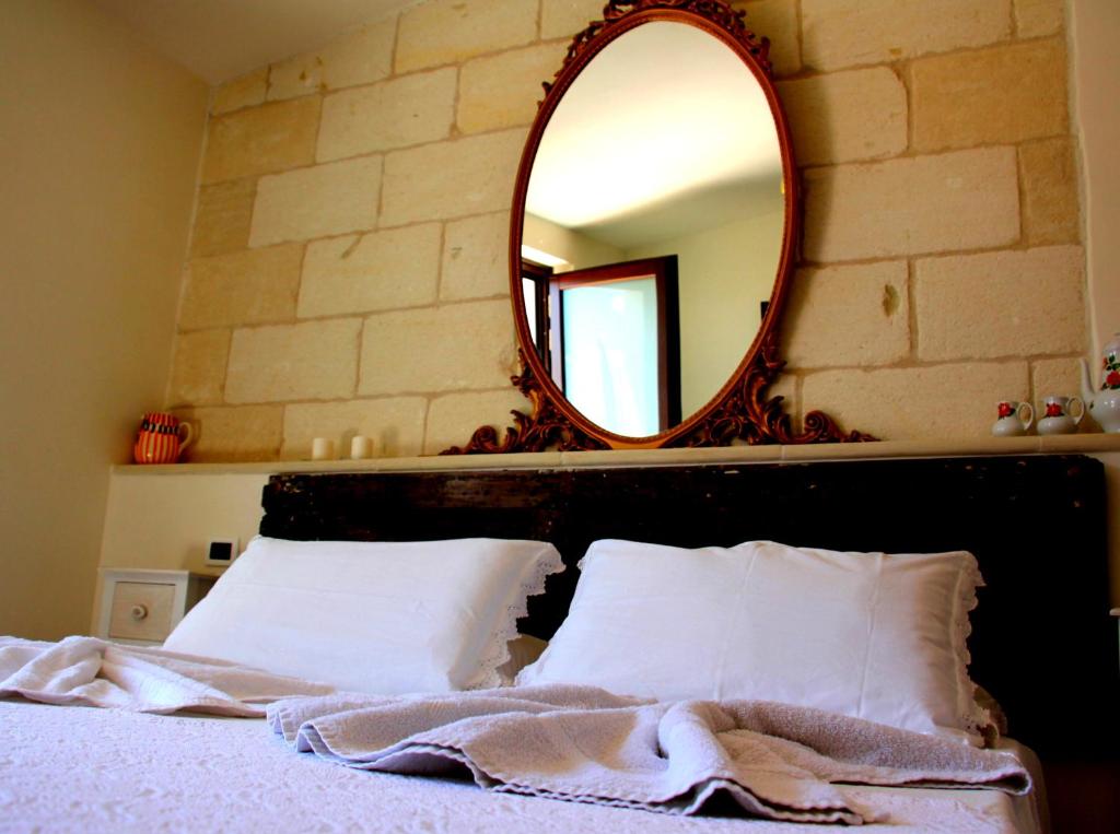 una camera da letto con specchio e letto con cuscini bianchi di Casa di Anna a Ostuni