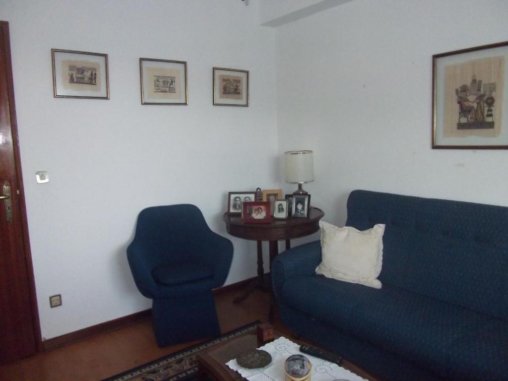 Apartamento Abril في Gouveia: غرفة معيشة مع أريكة زرقاء وكرسي