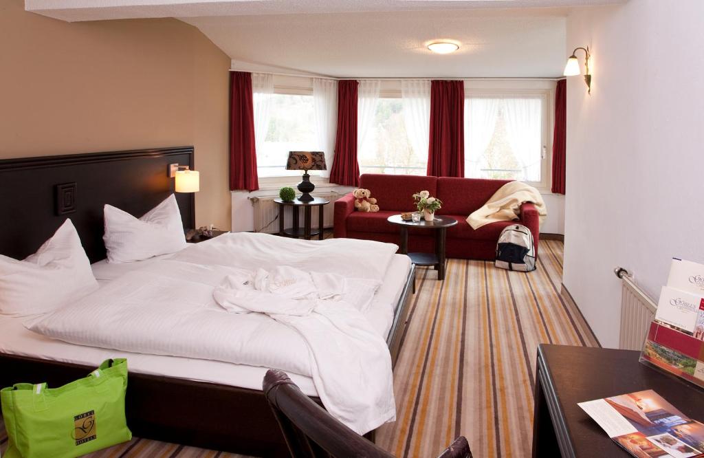 ein Schlafzimmer mit einem großen weißen Bett und einem Sofa in der Unterkunft Göbel's Gästehaus Hotel am Park in Willingen